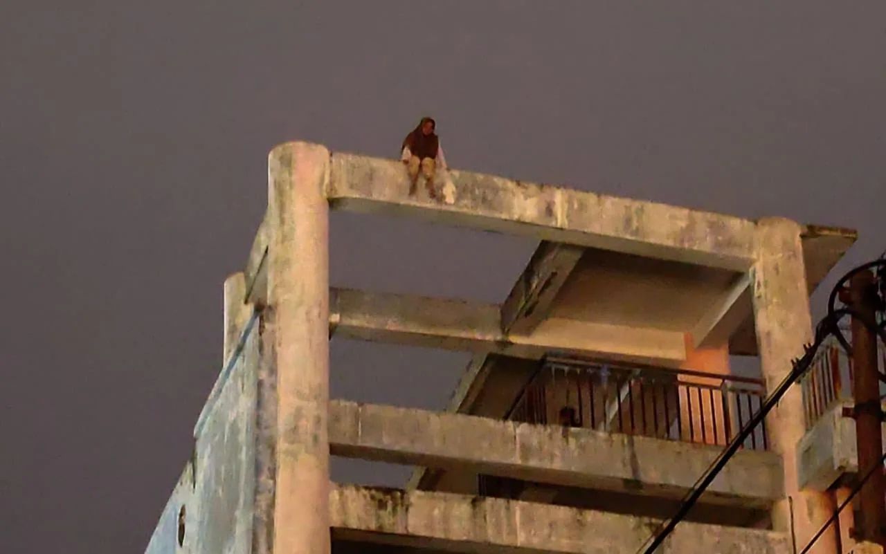 Seorang gadis duduk di lantai empat escape building Peukan Bada, Aceh Besar dan mengancam akan melompat namun berhasil dicegah oleh pihak kepolisian bersama keluarga, Jumat malam, 13 Desember 2024.