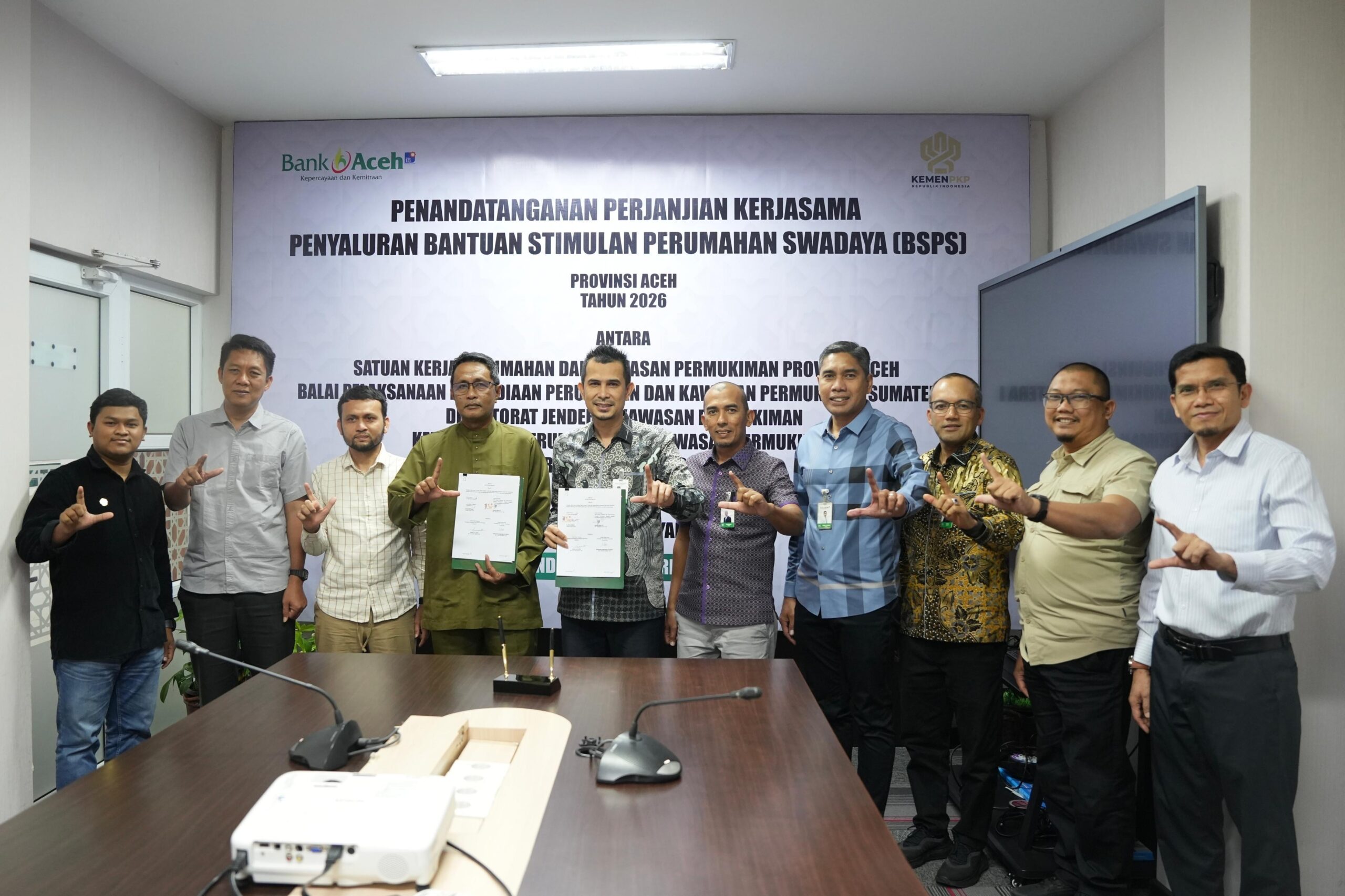 PENANDATANGANAN KERJASAMA BSPS 2026: Direktur Dana dan Jasa Bank Aceh, M. Hendra Supardi (kelima dari kiri), bersama Pejabat Pembuat Komitmen (PPK) Rumah Swadaya dan Pengembangan Kawasan Permukiman, Lukman Hakim (keempat dari kiri), menunjukkan dokumen Perjanjian Kerja Sama (PKS) Penyaluran Bantuan Stimulan Perumahan Swadaya (BSPS) Provinsi Aceh Tahun Anggaran 2026 di Kantor Pusat Bank Aceh, Banda Aceh, Kamis (12/3/2026).