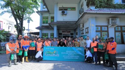 Wali Kota Banda Aceh, Illiza Saaduddin Djamal, bersama Dirut Bank Aceh Syariah, Fadhil Ilyas, dan Kepala DLHK3 Banda Aceh, Hamdani Basyah, berfoto bersama para petugas kebersihan (Pasukan Oranye) usai penyerahan paket bantuan Idul Fitri di halaman Kantor DLHK3 Banda Aceh, Jumat (12/3/2026).