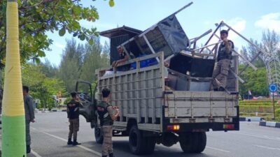 SITA BARANG PKL: Sejumlah personel Satpol PP WH Kota Banda Aceh mengangkut puluhan perlengkapan dagang milik PKL ke atas truk bak terbuka di sepanjang Jalan Syiah Kuala, Kecamatan Kuta Alam, Jumat (27/3/2026). Tindakan tegas ini dilakukan setelah para pedagang membiarkan barang-barang tersebut telantar di atas drainase usai bulan Ramadan, sehingga menciptakan kekumuhan dan melanggar ketertiban umum.